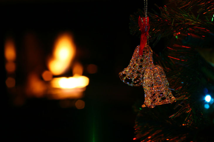 holiday ornaments on tree, fireplace in background