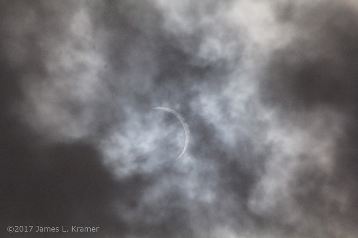 partial solar eclipse through cloud cover by James L. Kramer