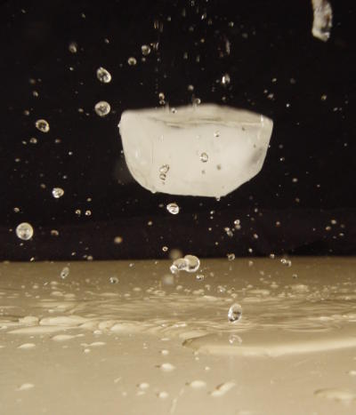 ice cube and water droplets in midair