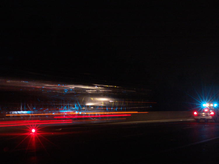 time exposure of car carrier passing police cruiser at night