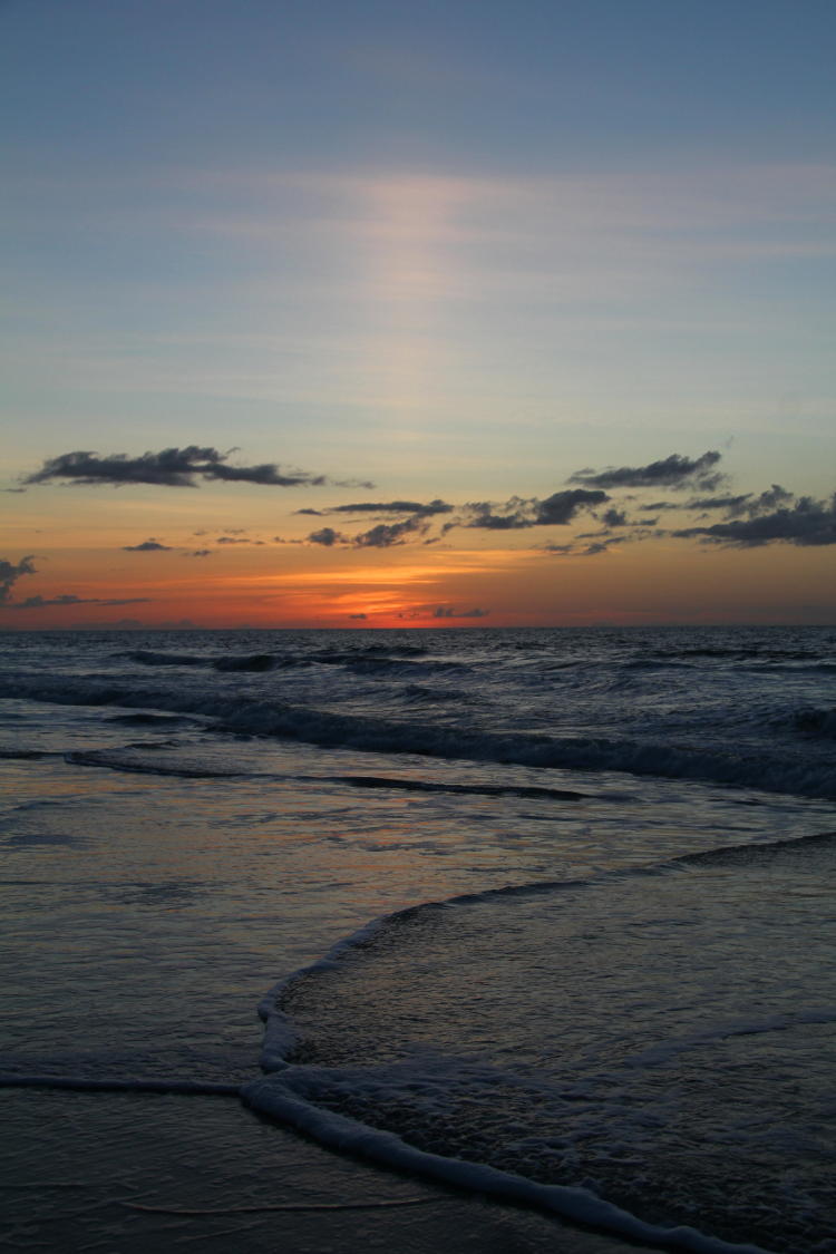 sun pillar before sunrise on beach