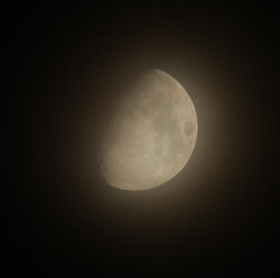 waxing gibbous moon through faint haze of clouds