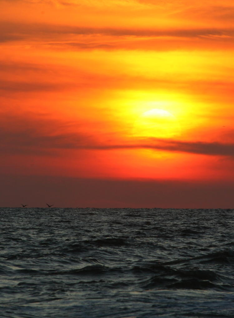 sun setting through clouds over ocean, Oak Island NC