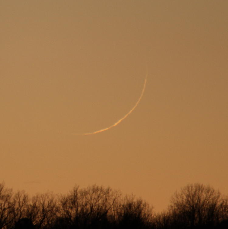sliver crescent moon distorted by atmosphere