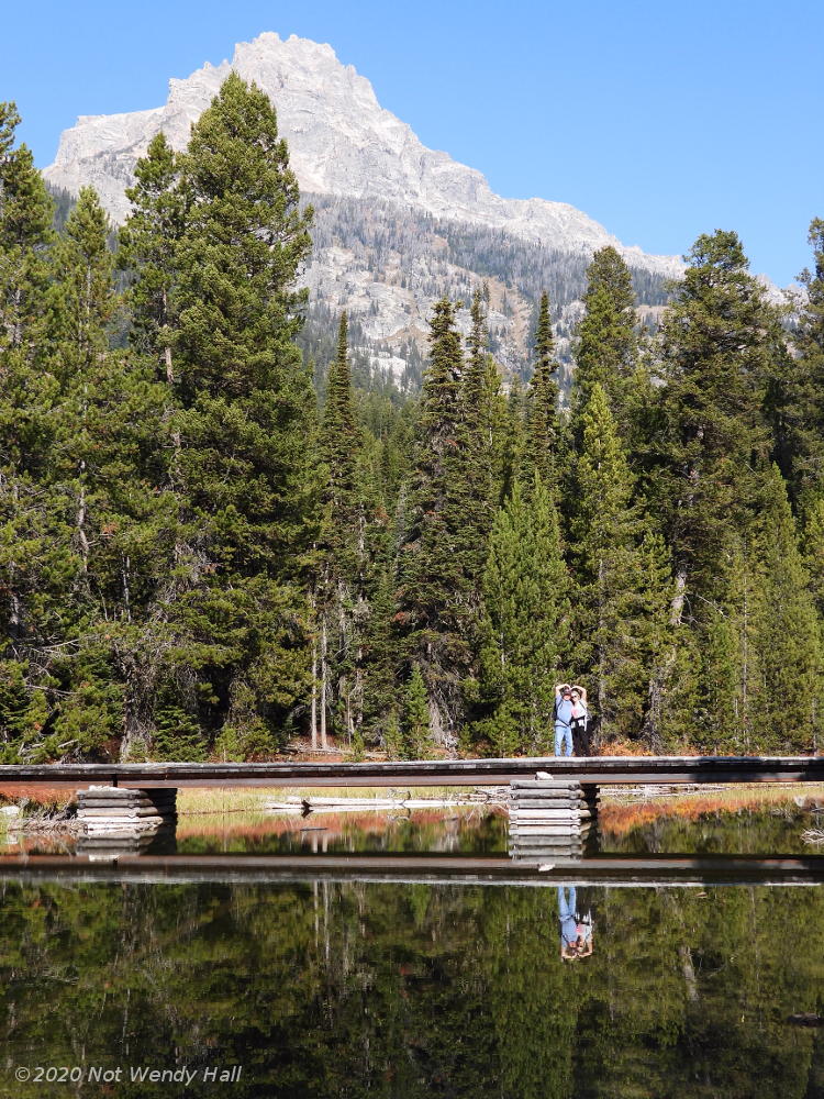 hikers posing by reflecting Taggert Lake with Grand Tetons in background, by not Wendy Hall