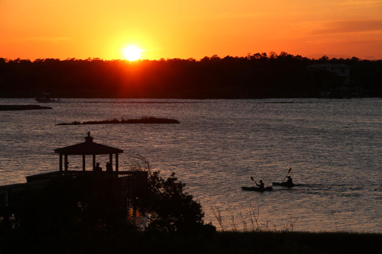 sunset over sound with gazebo and kayakers