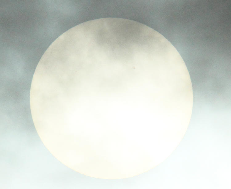 sun viewed through thin cloud cover allowing sunspots to be seen