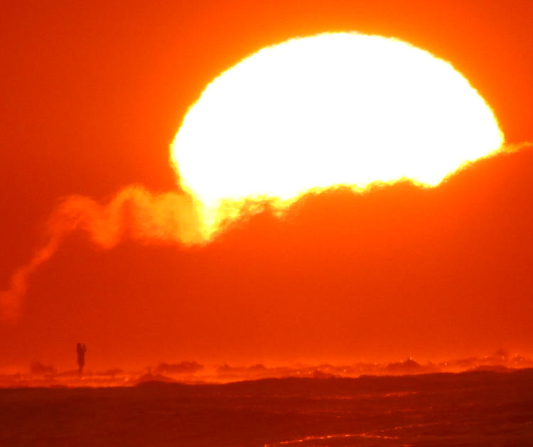 person pn horizon appearing to shoot enormous sun above them