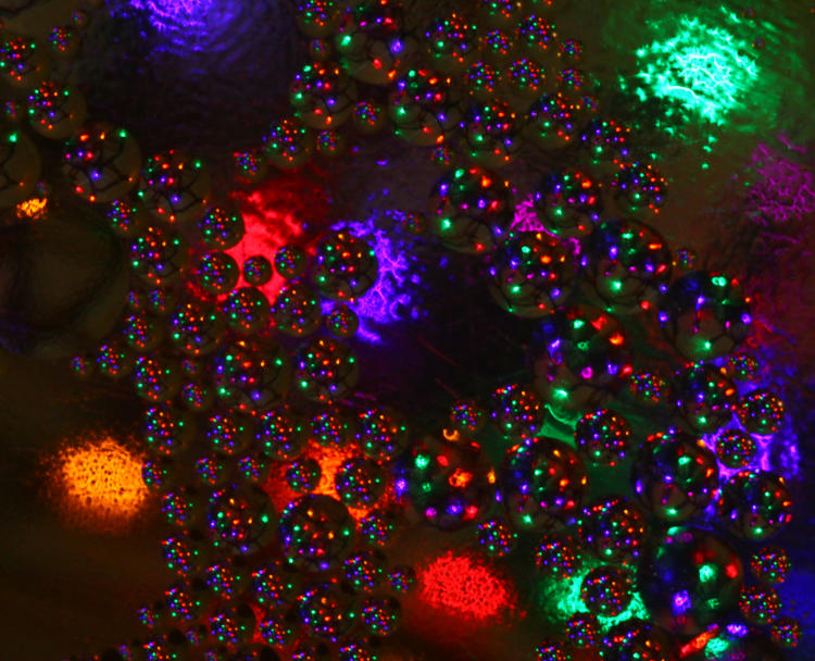 oil bubbles in shallow water with colored lights in background