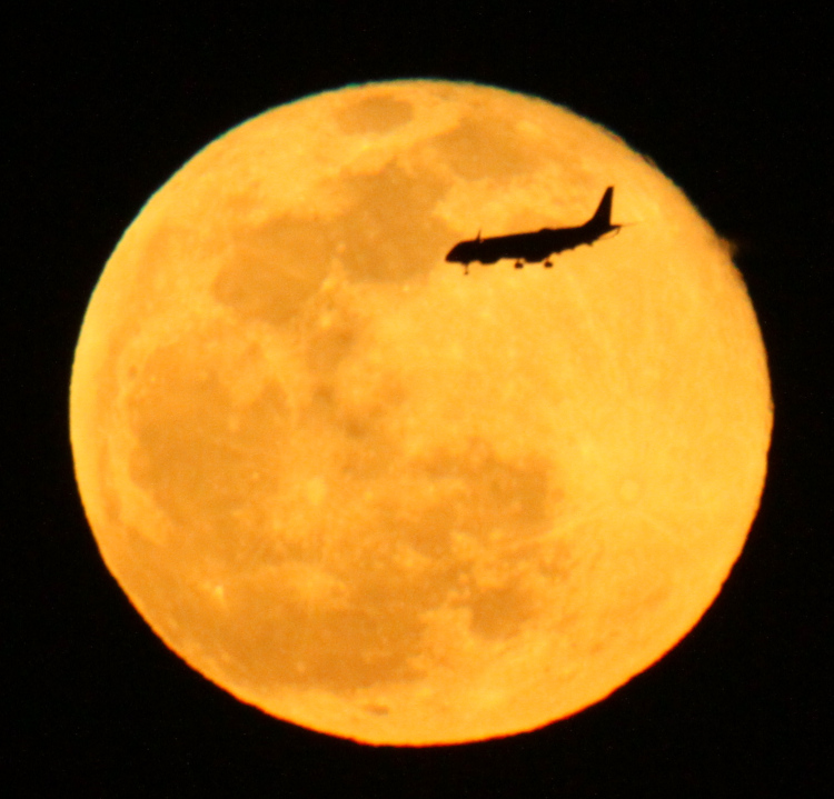 airliner passing against golden full moon