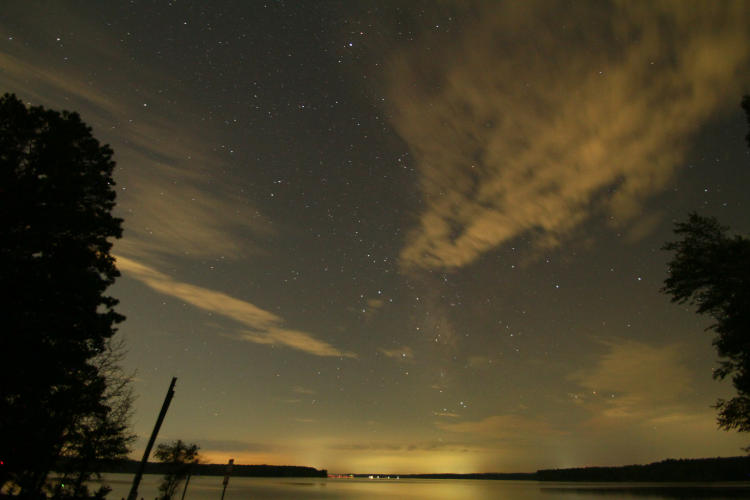 wide view of night sky out over Jordan Lake with scattered clouds and hint of Milky way