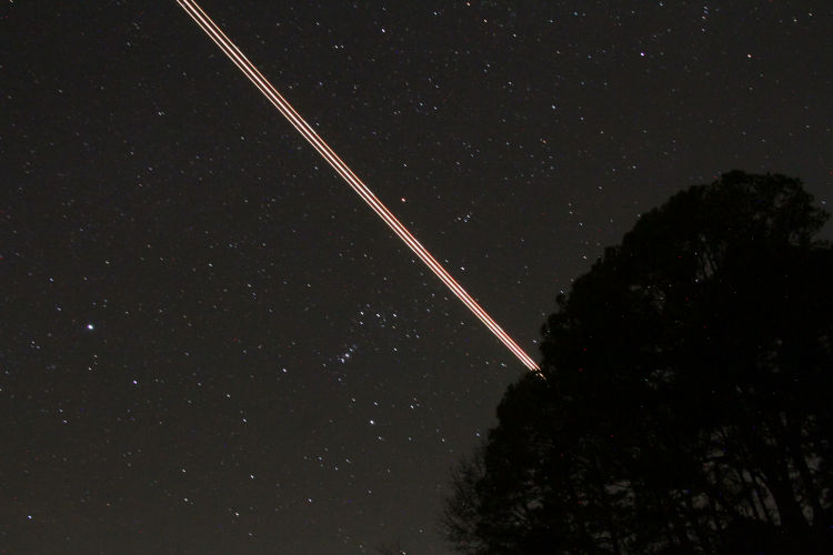 night time exposure of Orion with really close plane trail