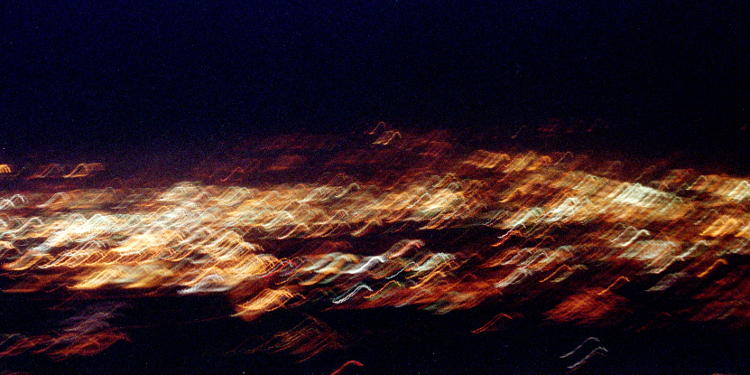 motion-blurred night exposure of city lights from landing aircraft