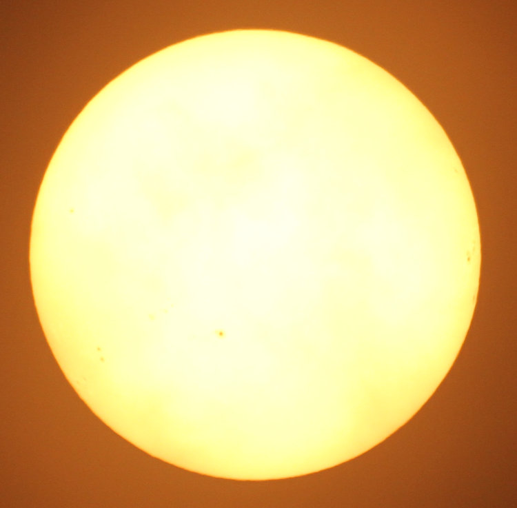 image of sun with solar filter showing sunspots and hints of clouds at edges