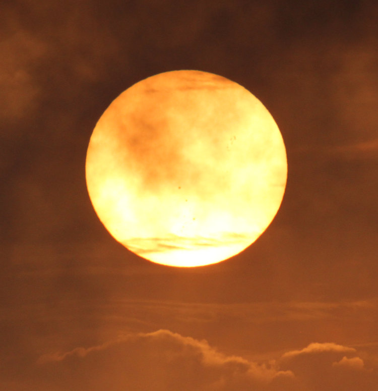 early morning sun through filtering clouds showing evidence of sunspots