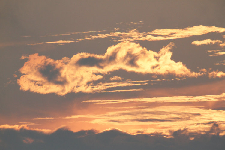 twisted clouds illuminated by sun hidden just below