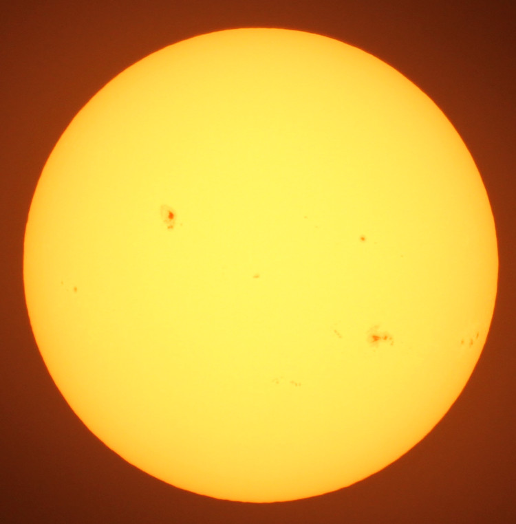 sun through solar filter showing numerous sunspots of varying sizes