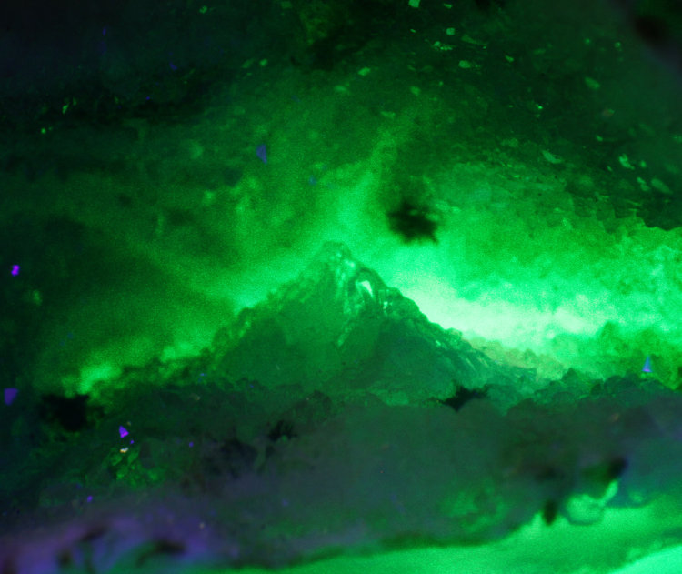 small geode illuminated by green laser through underside