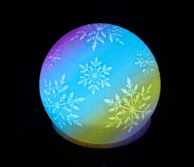 holiday ornament illuminated by color-changing base, photographed through moving diagonal slot