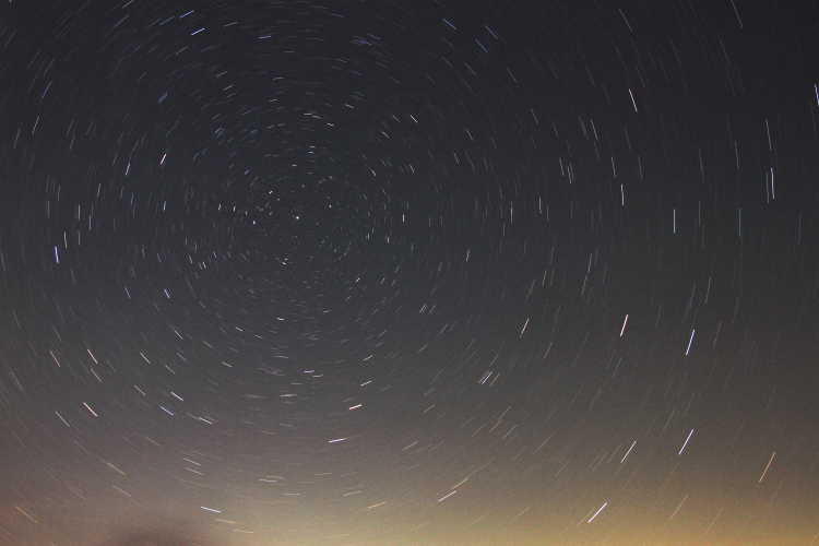 15-minute time exposure of night sky looking north proscribing arcs around Polaris, with contrast and color adjustments done digitally