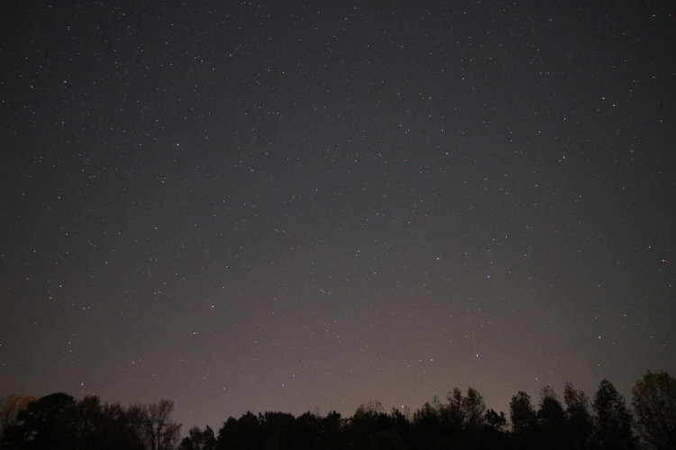 time exposure of night sky to north with faint vestige of aurora borealis showing pink on the horizon