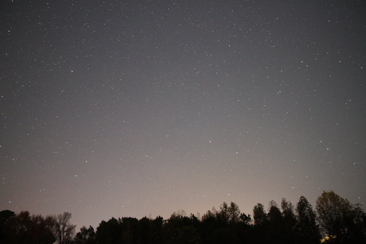 time exposure of night sky to the north showing faint vestige of aurora borealis as pink glow on horizon