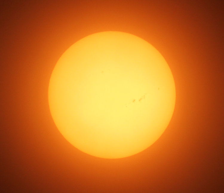 sun through solar filter, partially obscured by haze, showing unimpressive sunspots