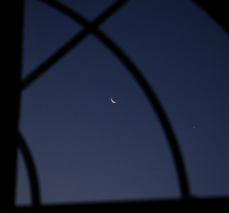 crescent moon and Venus through arched window in early morning 