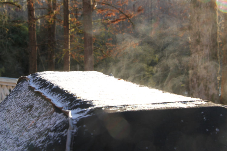 thin layer of snow atop grill giving off vapor in morning