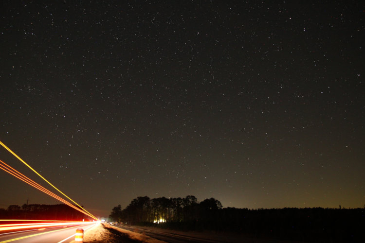 night time exposure of northern sky and edge of roadway with streaks from passing truck lights at edge