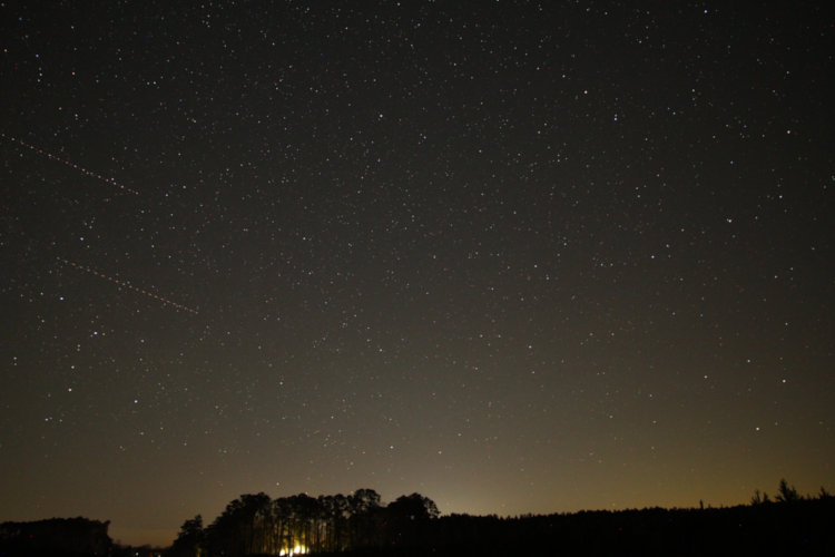 time exposure of northern sky showing at least two aircraft crossing the frame
