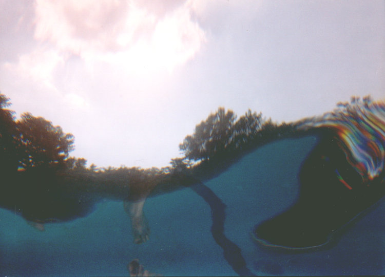 underwater shot of pool surface with foot reflection