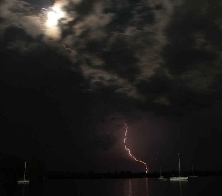 visible but blown out moon with lightning strike over Pamlico River