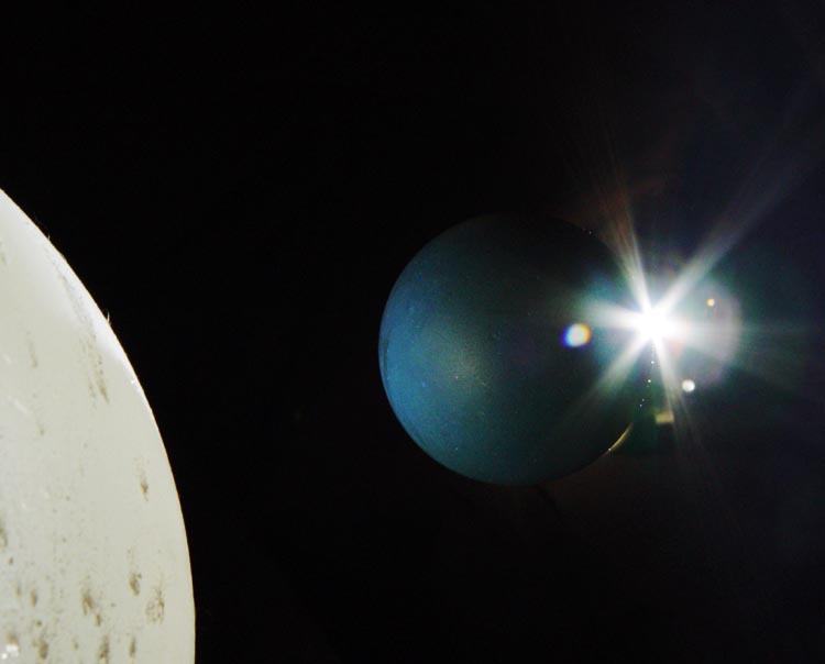 planetary composition with balloon, racquetball, and spot light source