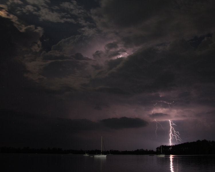 two-second exposure at night of lightning strike over Pamlico River with accent by moonlight