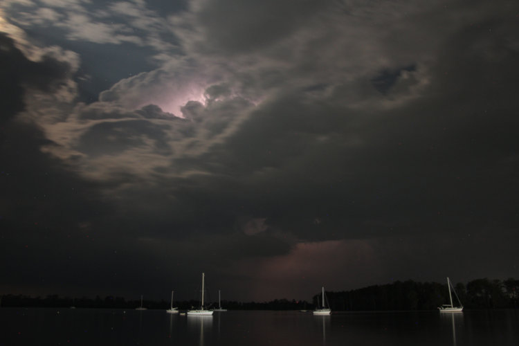 time exposure over Pamlico River with illumination from waterfront lights, moon, and lighting within clouds
