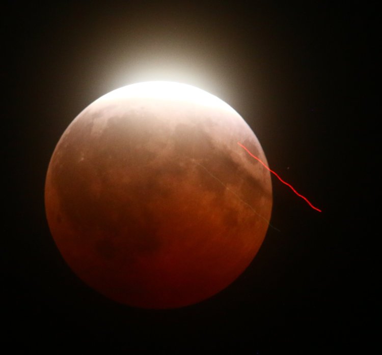 streaks of plane crossing partial lunar eclipse at 0.4 second shutter speed