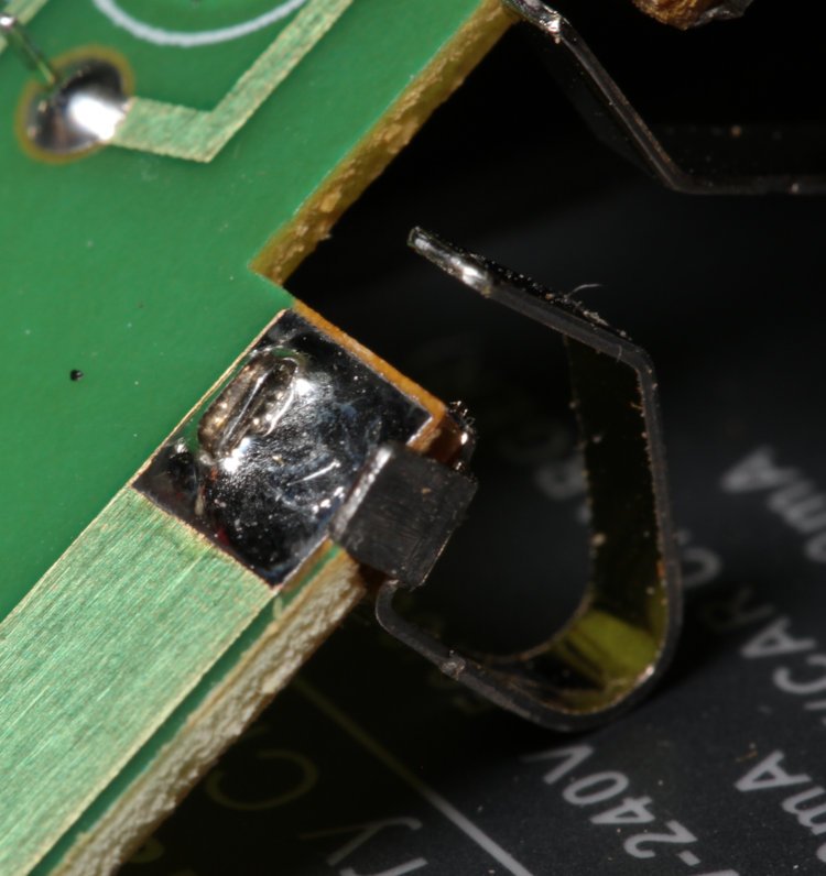 disassembled battery charger showing poor solder joint on AC contact tab