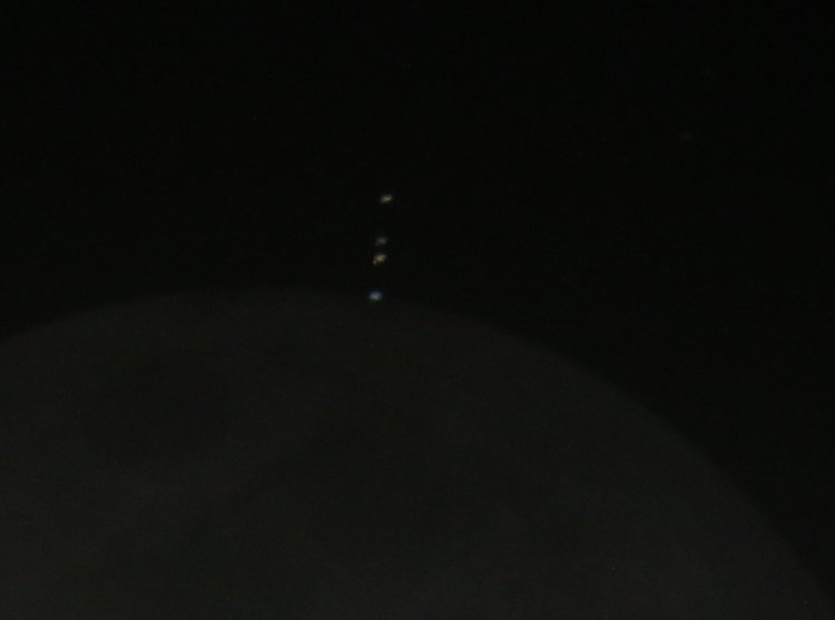 Eurpoa, Callisto, and Io appearing just above first vestige of Jupiter appearing from behind moon with earthshine