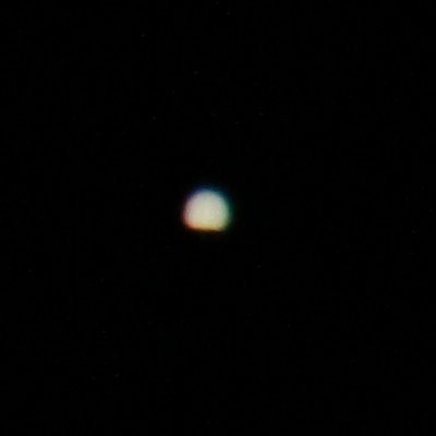 full-resolution crop of Jupiter almost entirely emerged from behind moon, exposure reduced to show stripes but eliminating evidence of moon