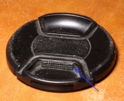 center-release lens cap with added hook tape for grip