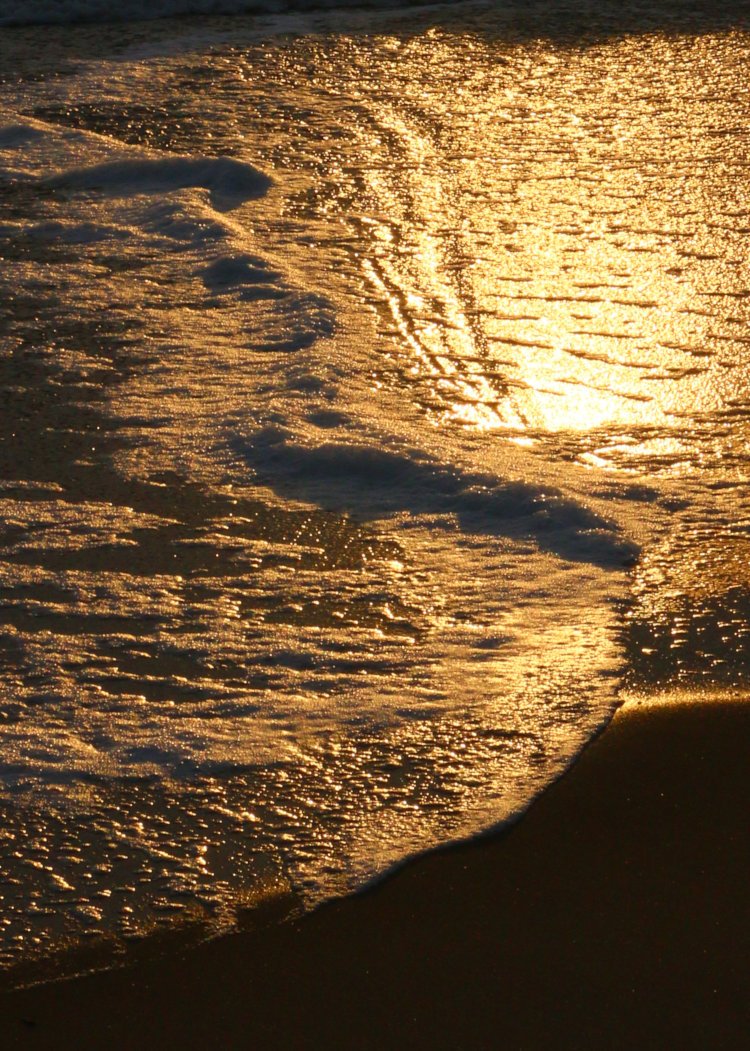 receding foam on beach at sunrise