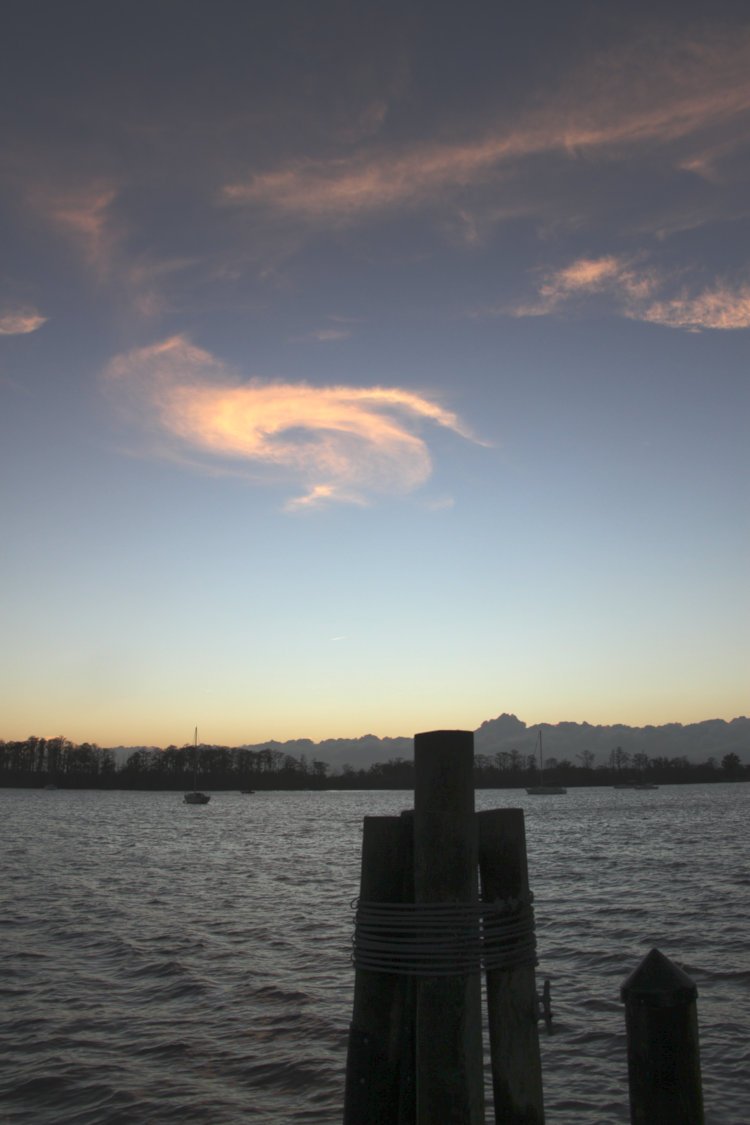 swirl of faintly colored clouds at twilight over waterfront