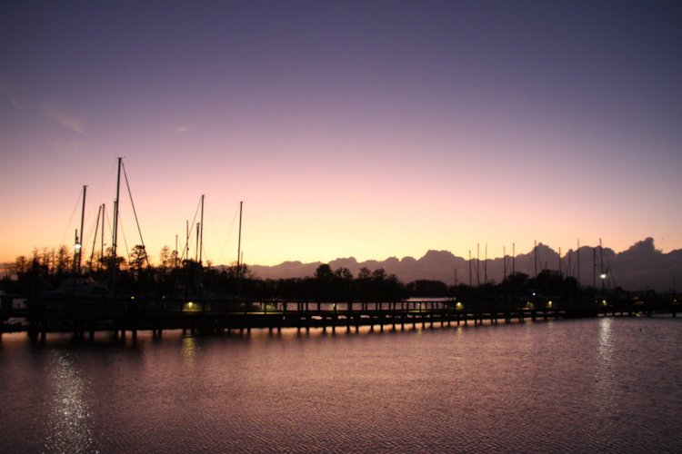 rich pink and cream afterglow behind boats on waterfront following sunset