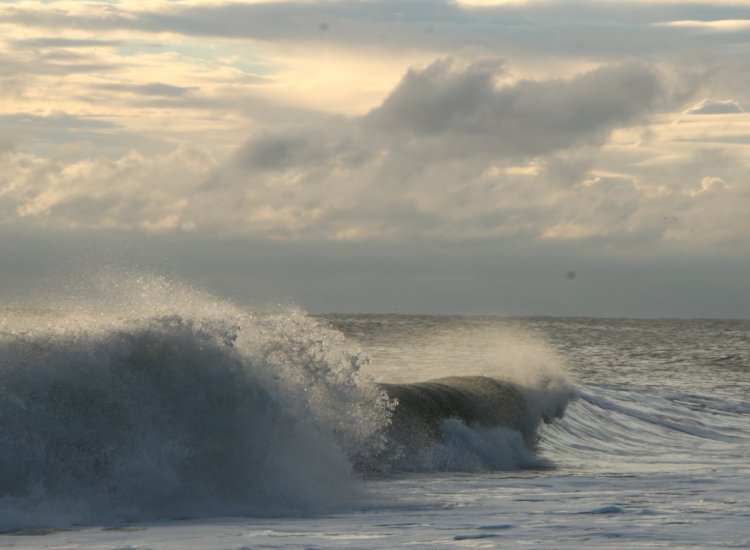 wind-driven spray lifting from the tops of ocean breakers